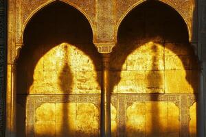 The archway is gold and has a shadow on it photo