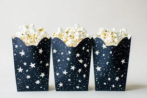 Three Black Popcorn Boxes with White Star Patterns Filled with Fresh Popcorn photo