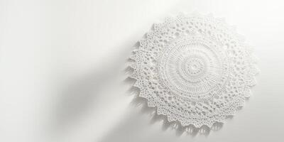 Detailed white crochet doily displayed on a plain white surface, showcasing intricate lace patterns and soft shadows. photo