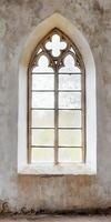 A window with a stone arch and a stained glass window. The window is open and the light is shining through it photo