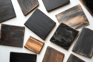 A collection of black and brown coasters with a brown stripe. Some of the coasters are square and some are rectangular photo