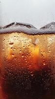 A glass of soda with ice cubes in it. The soda is fizzy and has a lot of bubbles photo