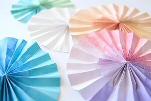 A bunch of paper fans are on a white background. The fans are in different colors and sizes photo