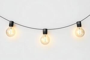 Three light bulbs hanging from a string. The bulbs are lit up. The string is black photo