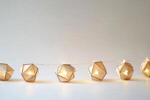 A string of lights with a white background. The lights are shaped like cubes. There are nine lights in total photo