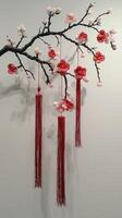 A decorative cherry blossom branch adorned with vibrant red tassels, set against a simple, elegant backdrop. photo