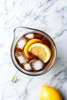 A glass pitcher of iced tea with a lemon slice in it photo