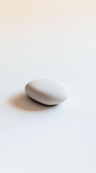 A single white stone on a smooth surface, embodying simplicity and tranquility in a minimalist style. photo