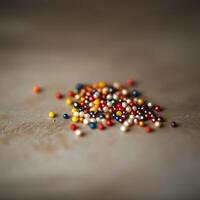 A vibrant collection of multicolored beads scattered on a neutral surface, showcasing a blend of colors and textures in a soft focus. photo