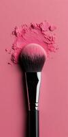 A pink makeup brush rests elegantly on a soft pink background, surrounded by a dusting of blush powder, showcasing beauty tools in an artistic arrangement. photo