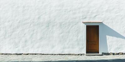 A simple wooden door situated on a textured white stucco wall, casting gentle shadows. The image captures minimalism and tranquility in outdoor architecture. photo