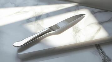 A stunning sharp knife rests on a pristine white surface, illuminated by brilliant light. This image captures elegance and modern design in a kitchen setting. photo