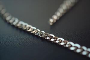 A detailed close up of a shiny silver chain showcasing intricate links against a dark background, perfect for highlighting elegance and craftsmanship in jewelry design. photo