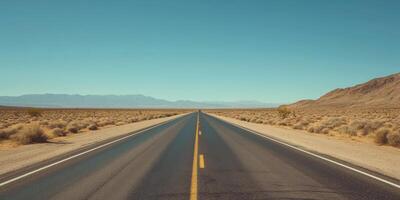Endless Desert Highway Under Clear Blue Sky with Distant Mountains in the Horizon photo