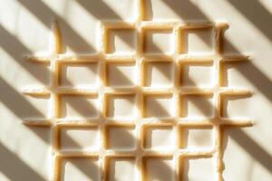 A captivating close up of a waffle texture, highlighted by soft shadows. The intricate grid pattern creates an inviting and cozy atmosphere perfect for food photography. photo