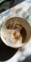 Artistic Swirls of Steam Rising from a Cup of Coffee in Sunlit Ambiance on a Decorative Tablecloth photo
