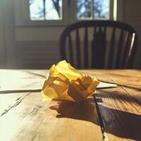 Sunlit Crumpled Paper on Wooden Table with Chair and Window in Background photo