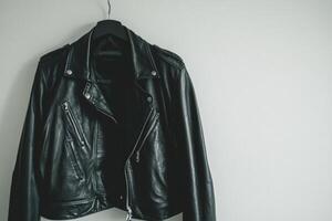 Black Leather Jacket Hanging on a Wall Against a Light Background photo