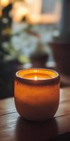 Cozy Candlelit Ambiance with Warm Glow in Rustic Ceramic Holder on Wooden Surface photo