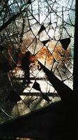 Silhouette of a Person Walking Behind a Broken Glass Window with Sunlight Streaming Through photo