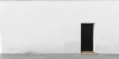 Minimalist Black Door on White Wall with Cobblestone Pavement photo