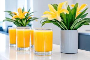 Fresh juice bar with vibrant golden-yellow juices and decorative floral arrangements on a sleek gray counter in a modern setting photo
