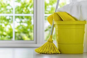 Mop and bucket in a bright corner of a room with sunlight filtering through large windows, creating a vibrant and clean environment for cleaning tasks photo