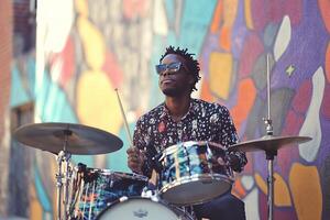 Street drummer playing a vibrant set in front of colorful graffiti wall photo