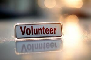 Close up of a volunteer badge with bold red text reflecting in sunlight photo