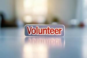 Closeup of a volunteer badge with bold red text reflecting sunlight photo