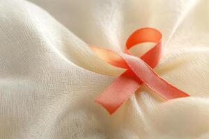 Close-up of an red awareness ribbon on asoft beige fabric background photo