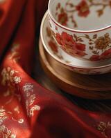 Ornate red gold tea cup with floral patterns on a vibrant red cloth background photo