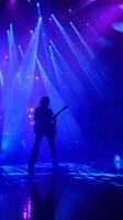 A person playing guitar in front of bright lights photo