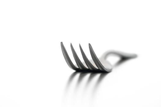 Sleek metallic fork resting on a reflective surface, capturing minimalist elegance in design photo