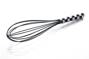 Whisk with black and white checkered handle resting on a clean, white surface in a bright kitchen setting photo