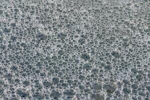 Tranquil bubbles create a mesmerizing surface texture on water at the break of dawn photo