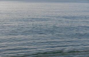 Calm waters reflecting the sky in a serene coastal setting during the golden hours of dusk photo