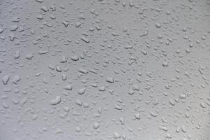 Raindrops shimmering on a windowpane creating a serene aquatic canvas during a quiet afternoon photo