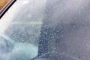 Raindrops gently collect on a car window during a cloudy afternoon in the city photo