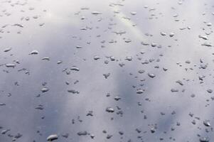 Raindrops dance on a reflective surface during a quiet afternoon in an urban setting photo