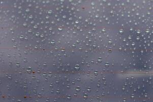 Raindrops create a mesmerizing pattern on a windowpane, reflecting the beauty of a cloudy afternoon photo