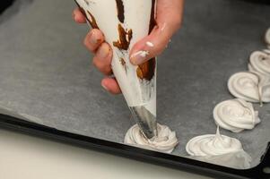 Mastering the art of meringue with swirls of chocolate on parchment photo