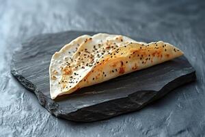 Gozleme with black cumin seeds resting on a slate plate photo