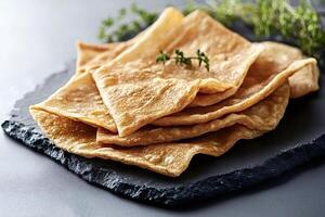 Stack of whole wheat pancakes lying on dark surface with thyme sprig photo