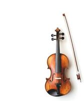 Antique wooden violin with bow resting beside it on light background photo
