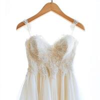 Elegant wedding dress hanging in bright natural light showcasing intricate lace and soft fabric details photo