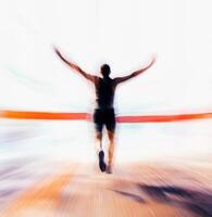 Runner crosses the finish line with arms raised during a vibrant marathon event at sunset photo