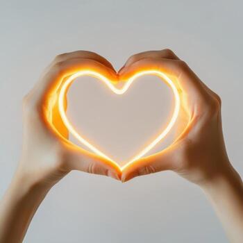 Hands create a glowing heart shape against a neutral background showcasing love and connection photo