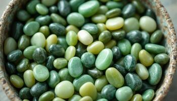 A bowl full of smooth polished jade stones in various shades of green and yellow photo