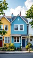 Vibrant row houses display a spectrum of color under a bright blue sky with puffy white clouds photo